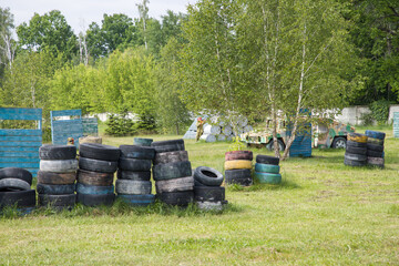 Paintball field with barrels, old tires and blue painted wooden crates for paintball game in summer day © Таня Микитюк