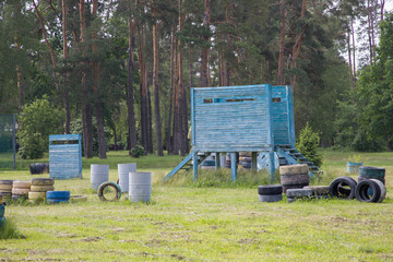 Paintball field with barrels, old tires and blue painted wooden crates for paintball game in summer day © Таня Микитюк