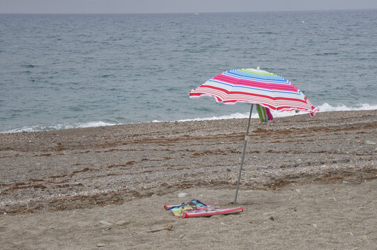 sombrilla para el sol en playa solitaria sucia de algas marinas