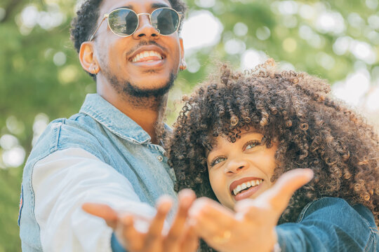 Two young people smiling and laughing together in a park, enjoying a sunny day with joy and positive energy