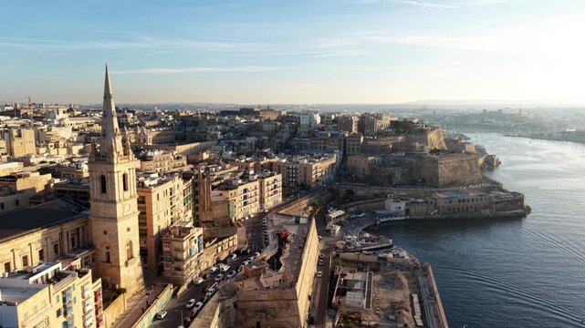 Aerial view of the Basilica of Our Lady of Mount Carmel spire and historic stone fortifications overlooking the harbor in Valletta, Port Region, Malta.