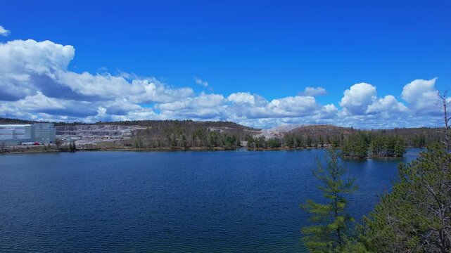 Turquoise lake water near open pit mine operation with sky. Mining operation, deep underground development of critical minerals for Artificial intelligence AI, EVs and hyperscale data centres.