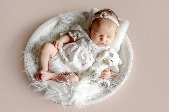 Newborn Baby Girl Sleeping In Wooden Bowl During A Photoshoot