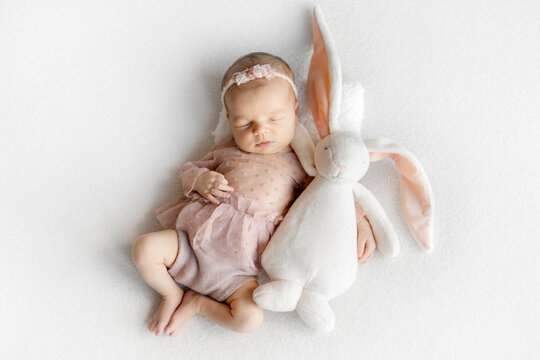 Newborn Girl Sleeping With Big Toy Bunny During A Photoshoot
