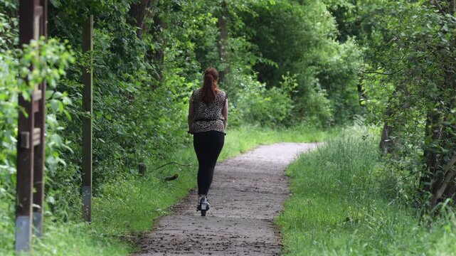 Woman riding an electric scooter on a park path