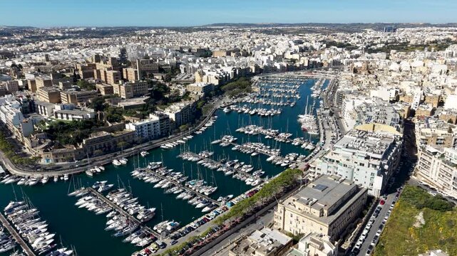 Aerial view of the Msida Marina filled with luxury yachts and sailboats surrounded by urban architecture in Ta' Xbiex, Eastern Region, Malta.