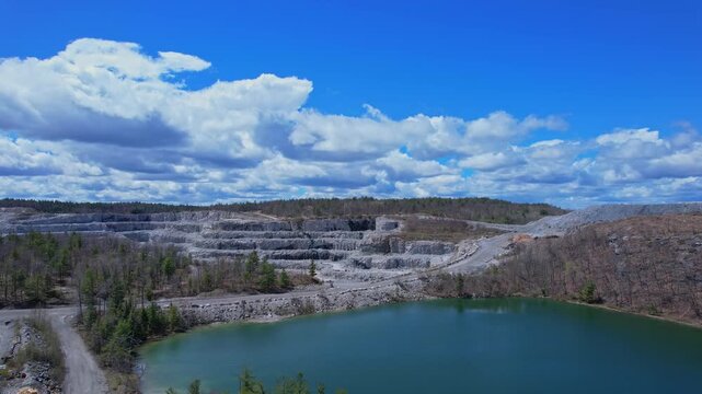 Turquoise lake water near open pit mine operation with sky. Mining operation, deep underground development of critical minerals for Artificial intelligence AI, EVs and hyperscale data centres.