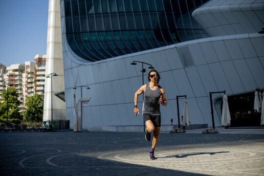 Runner sprints gracefully in a modern cityscape during bright daylight hours