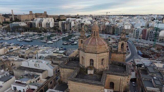 Aerial view of the historic Msida Parish Church dome and bell towers overlooking the marina filled with yachts and urban rooftops in Msida, Eastern Region, Malta.
