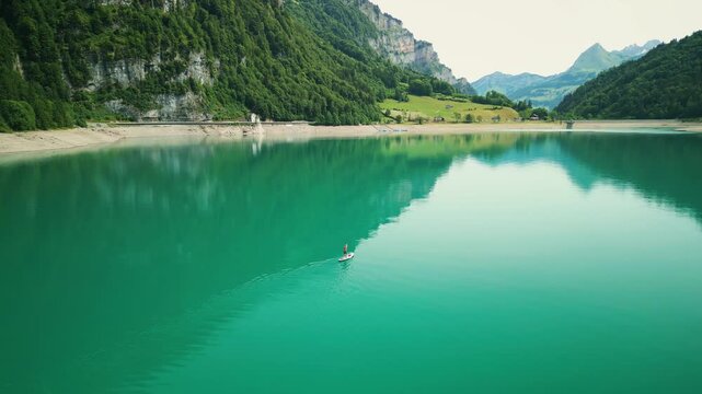 Person floating on SUP board along Kl&ouml;ntalersee, Glarus Canton, Switzerland