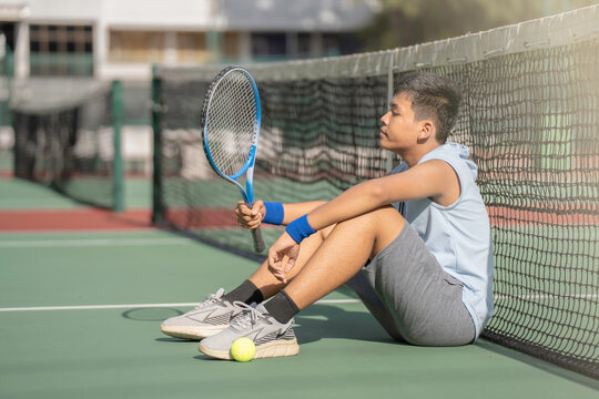 A boy is on the tennis court to play tennis.