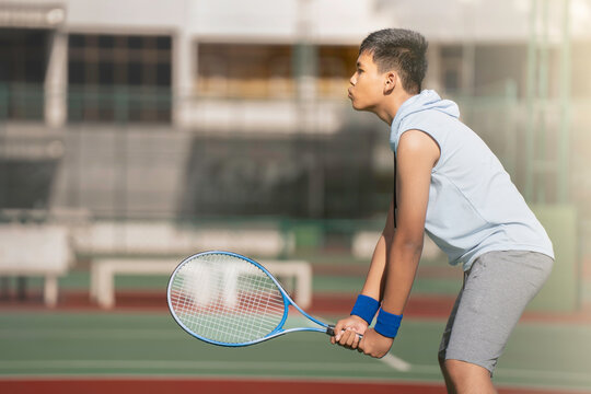 A boy is on the tennis court to play tennis.