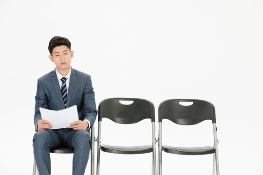 Young businessman waiting for job interview beside empty chairs