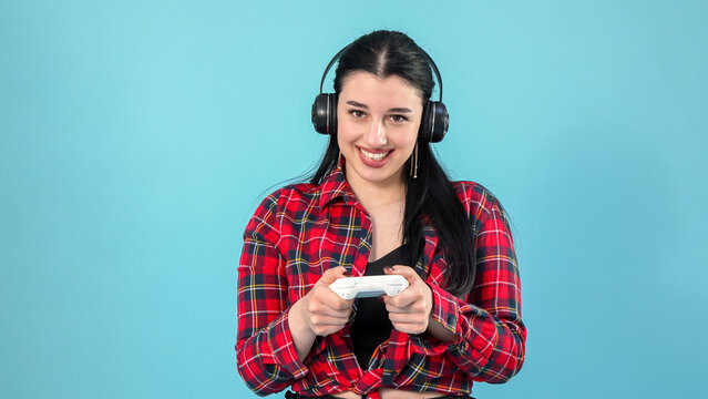 Focused girl wearing wireless headphones playing game with gamepad device