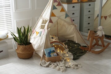 Cute wigwam with fairy lights and toys in stylish child's room © New Africa