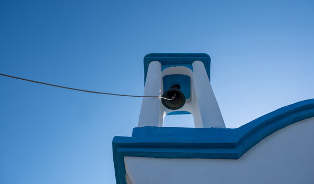 Blue and white Orthodox church bell tower from low angle in Ikaria island, Greece
