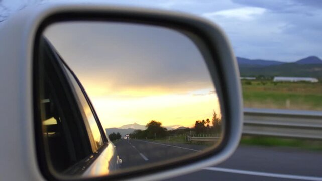 Sunset Through A Car Side Mirror
A beautiful sunset reflected in a car side mirror as the car moves along the road, gradually leaving it behind. Ideal for projects focused on landscapes, road trips, o
