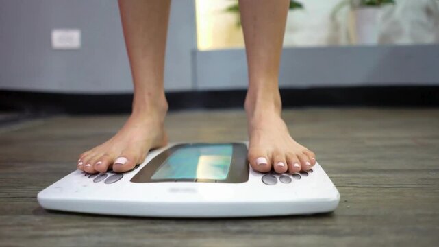 Woman Checking Weight by Stepping Barefoot Onto Digital Bathroom Scale