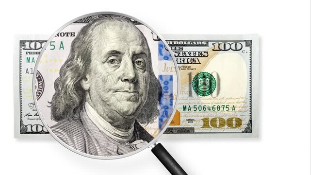 100 US dollar view through magnifying glass. US trade, duty, customs and tariffs war. Economic inflation, deflation or stagflation