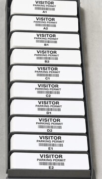 Vertical wall rack filled with identical white visitor parking permits management security identification facility organization corporate administration authorized stationary protocol