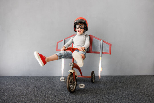 Happy child pretend to be astronaut. Funny kid with paper rocket. Little boy playing indoors