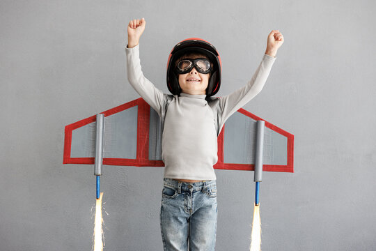 Happy child pretend to be astronaut. Funny kid with paper rocket. Little boy playing indoors