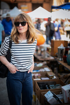 Stylish midlife woman browsing items at outdoor flea market on a sunny day