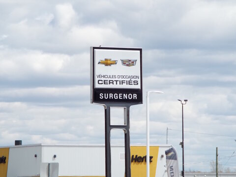 Gatineau, Quebec, Canada &ndash; May 8, 2026:A "Surgenor certified pre-owned vehicles sign standing outdoors on a cloudy day with a building behind on Boulevard Saint-Joseph.
