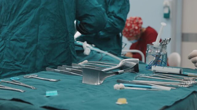 Close-up of sterile surgical instruments arranged on a surgical table in a modern hospital operating room. Medical equipment prepared for a surgical procedure while healthcare professionals work in