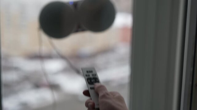 Housekeeper using remote control to operate modern robotic window cleaner washing glass from outside, innovative solution for domestic chores and home automation technology concept, slow motion.