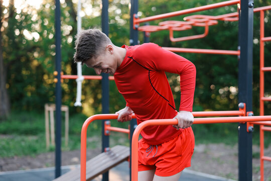 Athletic young man exercising on parallel bars at outdoor gym