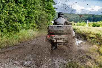 ATV Rider Splashing Through Muddy Off Road Trail Extreme Quad Bike Adventure in Countryside Landscape. Dynamic Action Photograph. Outdoor Motorsport. © Nomad Pixel