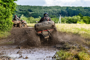 ATV Rider Splashing Through Muddy Off Road Trail Extreme Quad Bike Adventure in Countryside Landscape. Dynamic Action Photograph. Outdoor Motorsport. © Nomad Pixel