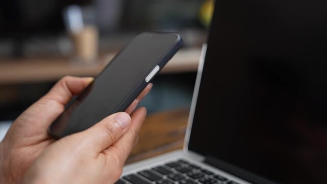 Person using mockup smartphone beside laptop for mobile communication, digital business workflow and online productivity. Blank screen mobile device concept for app promotion, marketing and technology