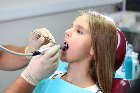 Pretty teenage girl with long hair at dentist appointment. Brushing your teeth. Prevention of caries. Concept of healthcare