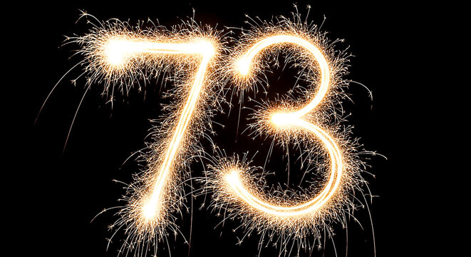 Vibrant sparkler fireworks creating the illuminated number 73 against a pitch-black backdrop, ideal for celebrations or milestone events.
