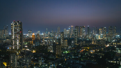 Fototapeta premium Cinematic aerial view of Mumbai city at night. Mumbai's iconic financial district with this stunning cityscape view—Shot of Mumbai Skyline, high-rise buildings in South Mumbai, Maharashtra, India.