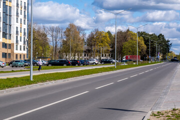Quiet Suburban Street With Apartment Buildings, Parked Cars, Lampposts and Pedestrian on Sidewalk © Eugeniusz