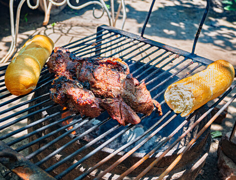 Costillas de carne vacuna cocin&aacute;ndose lentamente sobre parrilla durante proceso de asado argentino