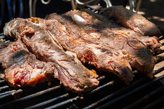 Costillas de carne vacuna cocin&aacute;ndose lentamente sobre parrilla durante proceso de asado argentino