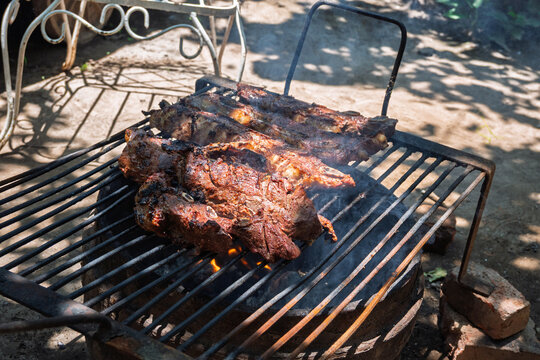 Costillas de carne vacuna cocin&aacute;ndose lentamente sobre parrilla durante proceso de asado argentino
