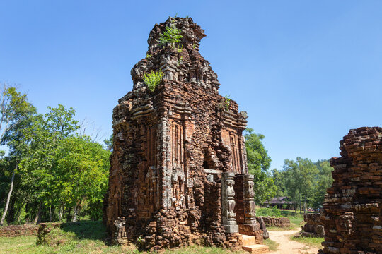 Tall ancient brick tower monument of Group B ruins standing under a clear blue sky at My Son Sanctuary