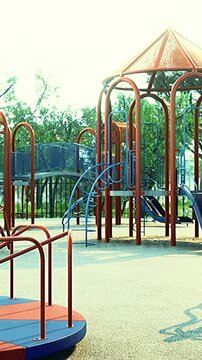 Children enjoy outdoor play at a playground in a city park with slides and climbing frames. Parents observe as kids climb and slide in bright sunlight.