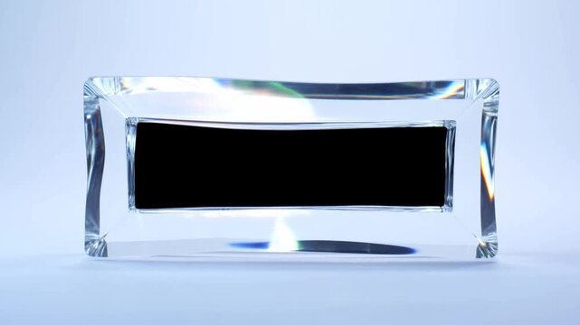 Slow dolly forward shot of glass rectangular block with black inset sliding and rotating on white seamless studio tabletop with subtle prism reflections and bright cool lighting