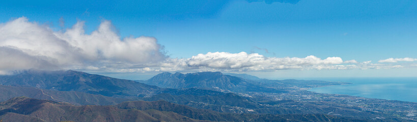 Obraz premium Sweeping mountain panorama revealing the sparkling Mediterranean Sea, Estepona and distant Gibraltar beneath open skies from Sierra Bermeja in Spain.