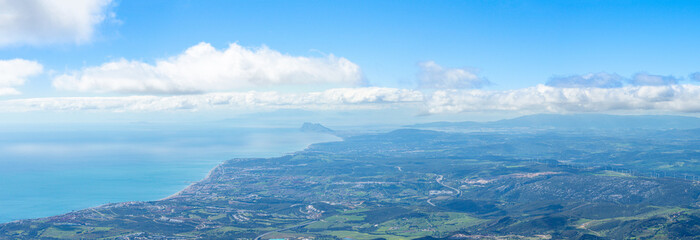 Obraz premium Sweeping mountain panorama revealing the sparkling Mediterranean Sea, Estepona and distant Gibraltar beneath open skies from Sierra Bermeja in Spain.