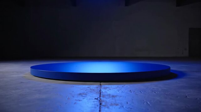 Blue illuminated circular platform rising on dark concrete floor for product showcase and luxury presentation