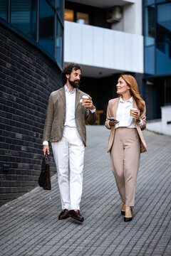 Business people walking and talking outdoors during coffee break