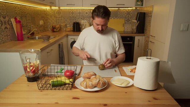 Man slicing kiwi on cutting board in rustic kitchen morning