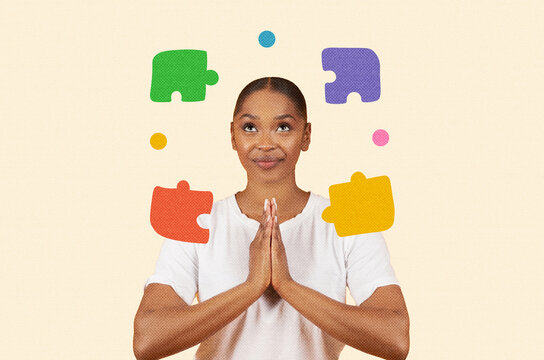 Focused Black Woman In Her 30s With Hands Together Contemplating Various Puzzle Pieces, Smiling In Modern Office Setting. Puzzle Concept Reflecting Problem Solving And Creativity